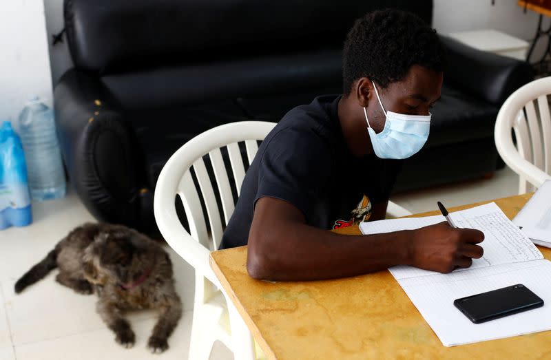 Mohamed Gueye a Senegalese migrant who arrived on the island in a boat receives Spanish lessons in Tito Martin's private garage in Las Palmas