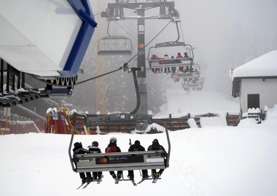 Skiers ride the lift line on Mount Kopaonik, Serbia, Thursday, Dec. 9, 2021. As most of Europe reintroduces measures to help curb the spread of the omicron variant, Bosnia, to the delight of its winter tourism industry, still maintains a relatively laissez-fair approach to the soaring COVID-19 infection numbers across the continent. (AP Photo/Marjan Vucetic)