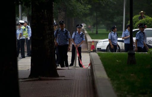 Policemen stand outside the court during an appeal hearing for disabled Chinese rights defender Ni Yulan -- to stop journalists from conducting interviews, taking photos, or video footage -- in Beijing. The court reduced by two months the jail sentence for the disabled activist, but upheld her conviction for "picking quarrels"