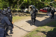 Police in riot gear charge during a training exercise, near a burned passenger van, center, allegedly torched by gangs on Jan. 4, 2023, in Cacahoatan, Mexico, Wednesday, Jan. 18, 2023. Local authorities have formed an anti-gang task force and posted police at transport hubs, and last month Mexico's military deployed an additional 350 soldiers to communities along the Guatemalan border. (AP Photo/Moises Castillo)