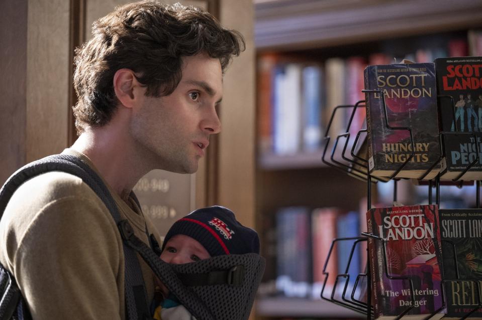 Joe carries his baby son at a library in "You" Season 2