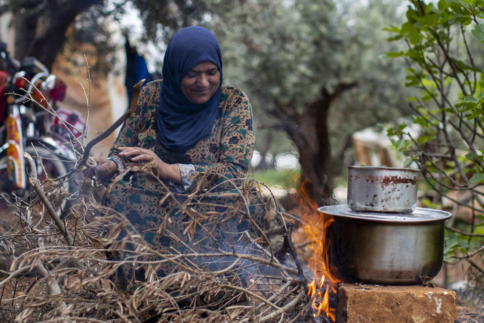 A Syrian refugee cooks food on a fire, at an informal refugee camp, in the town of Rihaniyye in the northern city of Tripoli, Lebanon, Thursday, April 8, 2021. For many Syrian refugee families in Lebanon, Ramadan comes as a hard life of displacement has gotten even harder after a pandemic year that deepened economic woes in their host country. (AP Photo/Hassan Ammar)