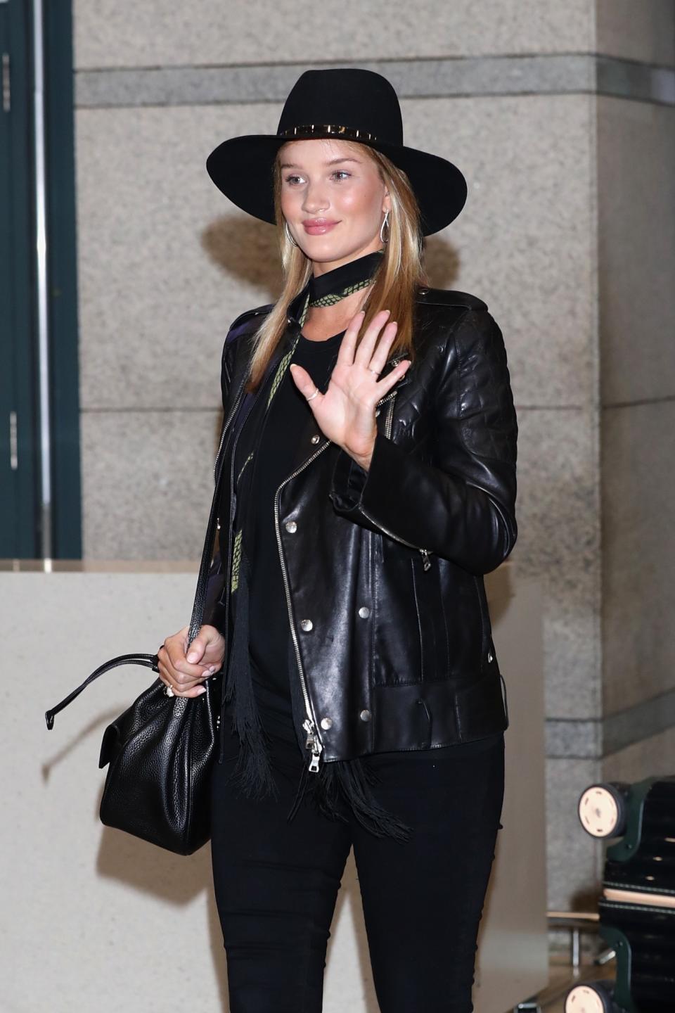 Rosie Huntington-Whiteley styles her chic Rockins scarf with a black fedora and slick leather jacket in South Korea.