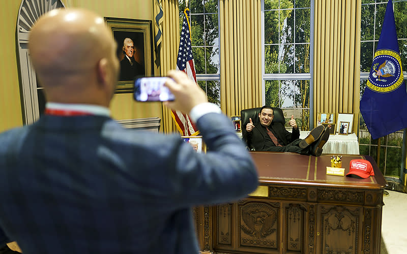 An attendee takes a photo in a fake Oval Office during the Conservative Political Action Conference (CPAC) at the Gaylord National Resort and Convention Center in National Harbor, Md., on Thursday, March 2, 2023. <em>Greg Nash</em>