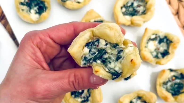 spinach and feta tarts on sheet, in hand