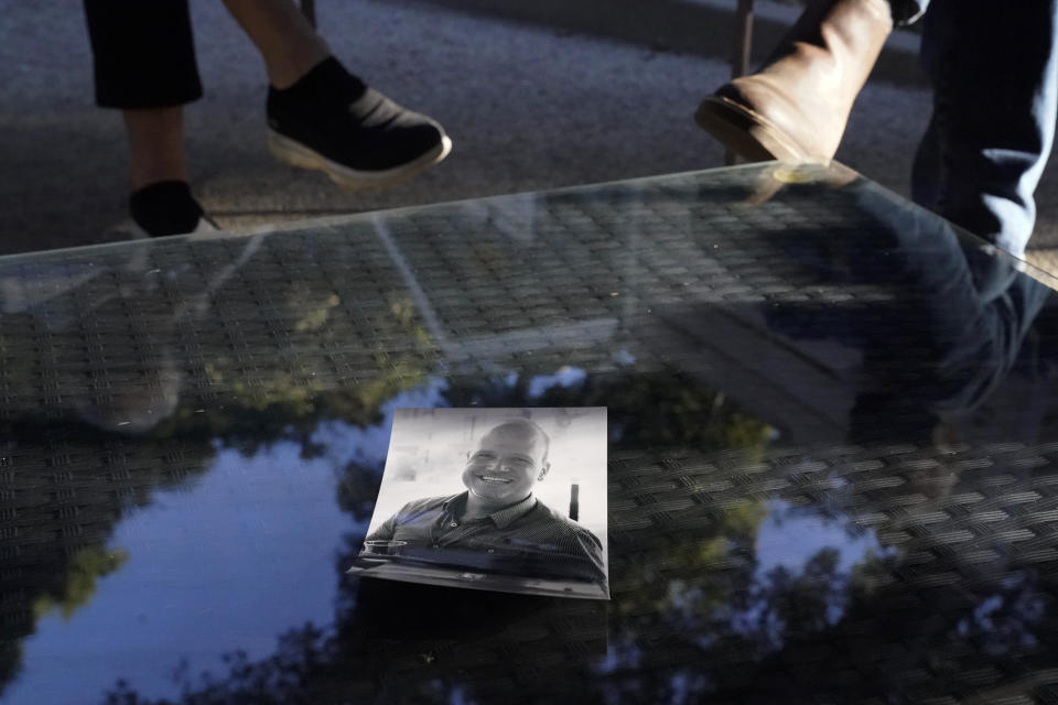 A photo of Charles McIlvain, center, lays on a table between his parents, Kathleen McIlvain, left, and Clark McIlvain, at their home on Thursday, Dec. 3, 2020, in Woodland Hills, Calif. Charles McIlvain was one of 34 people killed when dive boat Conception caught fire and sank off the coast of California on Sept. 2, 2019. (AP Photo/Ashley Landis)