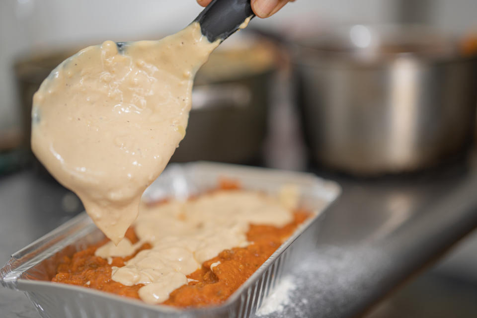 Spooning cheese sauce into a baking dish