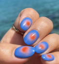 <p>A red, <a href="https://www.goodhousekeeping.com/beauty/nails/g4930/ombre-nails/" rel="nofollow noopener" target="_blank" data-ylk="slk:ombre;elm:context_link;itc:0;sec:content-canvas" class="link ">ombre</a> circle on a blue base coat adds dimension and will make your nails pop this Fourth of July.</p>