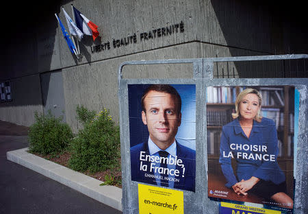 New official posters for the candidates for the 2017 French presidential election, Emmanuel Macron (L), head of the political movement En Marche !, or Onwards !, and Marine Le Pen (R), French National Front (FN) political party leader, are displayed in Fontaines-sur-Saone, near Lyon, France, April 30, 2017. REUTERS/Robert Pratta