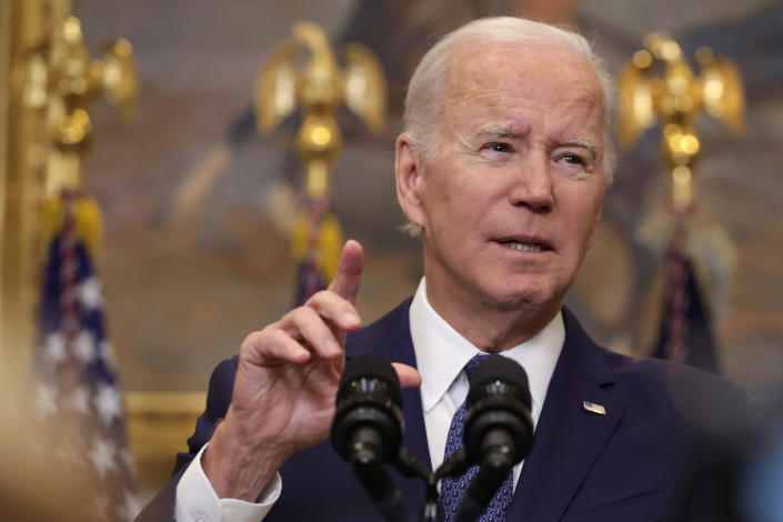 President Biden raises his index finger as he makes a point at the microphone. 