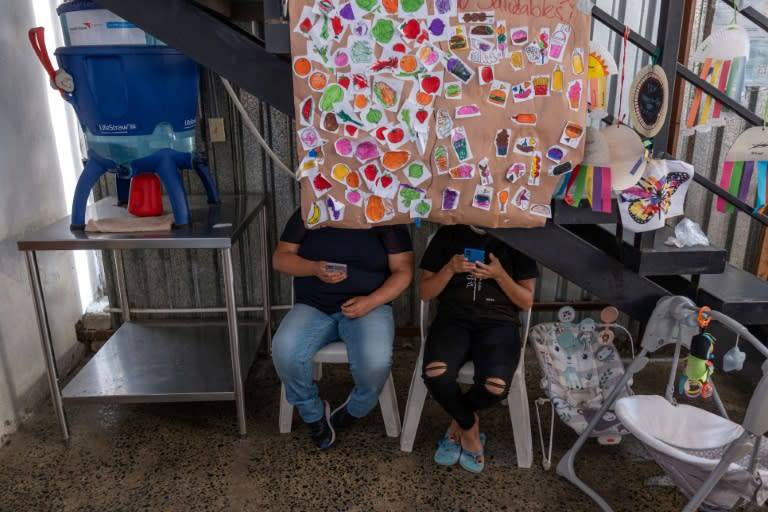 Unos solicitantes de asilo miran sus teléfonos móviles el 4 de junio de 2024 en un refugio en Tijuana, México (Guillermo Arias)