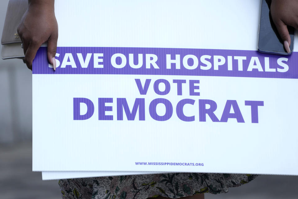 A protester holds a sign during a response by Mississippi Democratic Party Chairman State Rep. Cheikh Taylor, D-Starkville, to Mississippi Gov. Tate Reeves' announcement of a proposal that he says should alleviate financial problems for hospitals, Thursday, Sept. 21, 2023, in Jackson, Miss. (AP Photo/Rogelio V. Solis)