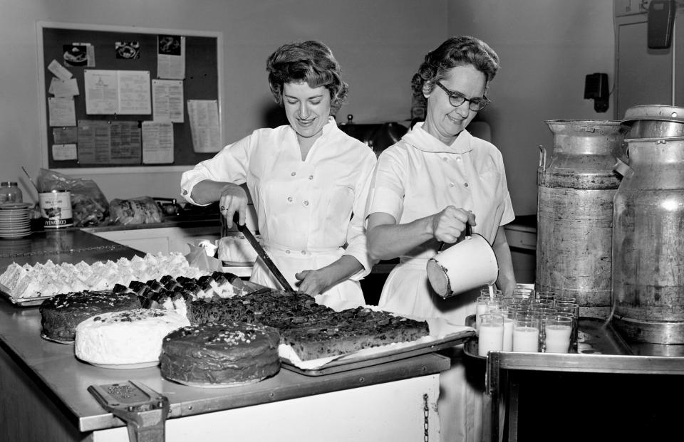 Ann Parson, left, slices the first of 60 pounds of fruit cake baked in the Baptist Hospital kitchen for employee Christmas parties Dec. 20, 1962, as Grace Dycus, food service supervisor, pours the first of 50 gallons of eggnog to be mixed.
