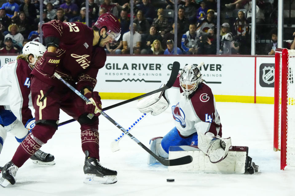 Colorado Avalanche goaltender Alexandar Georgiev, right, makes a save against a shot by Arizona Coyotes center Jack McBain, left, during the second period of an NHL hockey game Sunday, March 26, 2023, in Tempe, Ariz. (AP Photo/Ross D. Franklin)