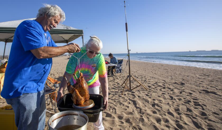 HUNTINGTON BEACH, CA - NOVEMBER 25: Chip Margelli and wife Janet Margelli of Garden Grove are deep-frying a turkey in peanut out at Bolsa Chica State Beach at on Thursday, Nov. 25, 2021 in Huntington Beach, CA. He says he has been celebrating Thanksgiving at the beach for over 15 years. (Francine Orr / Los Angeles Times)