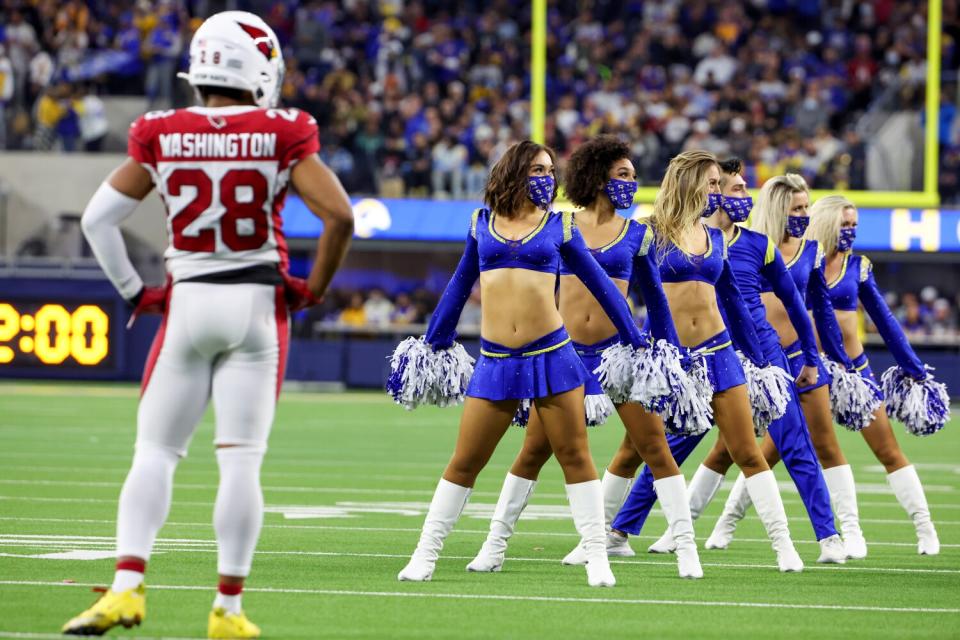 Cardinals safety Charles Washington looks on as Rams cheerleaders perform on the field during a break