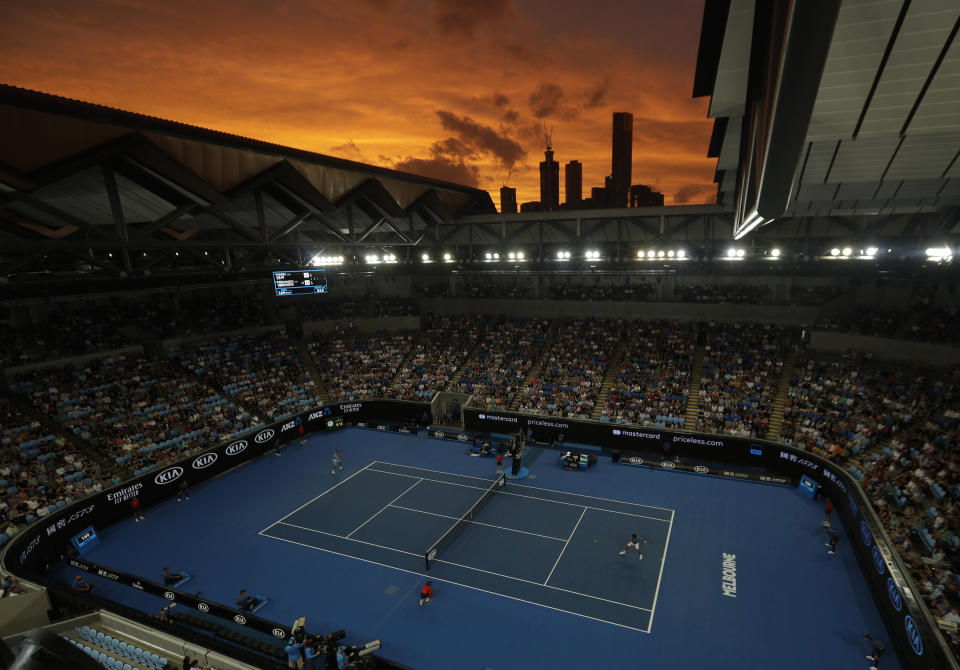 The sun sets over the Melbourne skyline as Croatia's Marin Cilic and Spain's Fernando Verdasco play their third round match at the Australian Open tennis championships in Melbourne, Australia, Friday, Jan. 18, 2019. (AP Photo/Mark Schiefelbein)