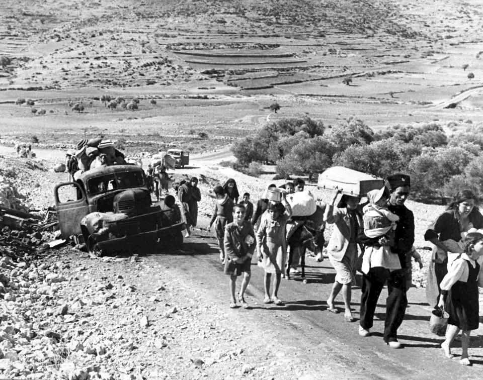 FILE - A group of Arab refugees walks along a road from Jerusalem to Lebanon, carrying their belongings with them on Nov. 9, 1948. The group was driven from their homes by attacks in Galilee. For the first time, the United Nations will officially commemorate the flight of hundreds of thousands of Palestinians from what is now Israel on the 75th anniversary of their exodus, an action stemming from the U.N.’s partition of British-ruled Palestine into separate Jewish and Arab states. (AP Photo/Jim Pringle, File)