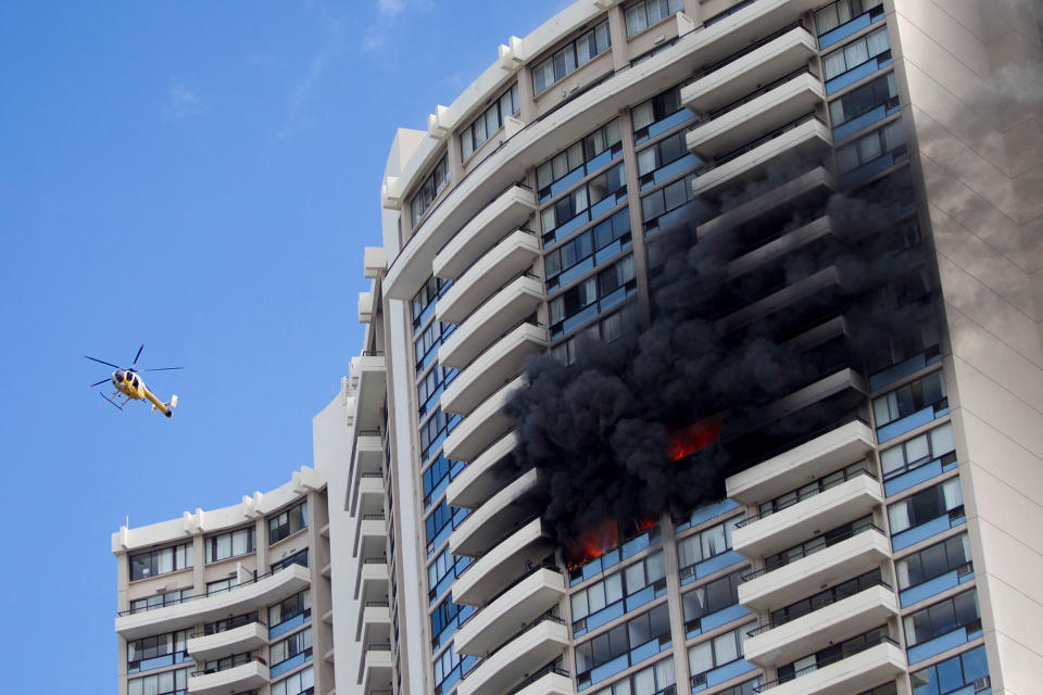 <p>A Honolulu Fire Department helicopter flies near a fire burning on a floor at the Marco Polo apartment complex, Friday, July 14, 2017, in Honolulu, Hawaii. (Photo: Marco Garcia/AP) </p>