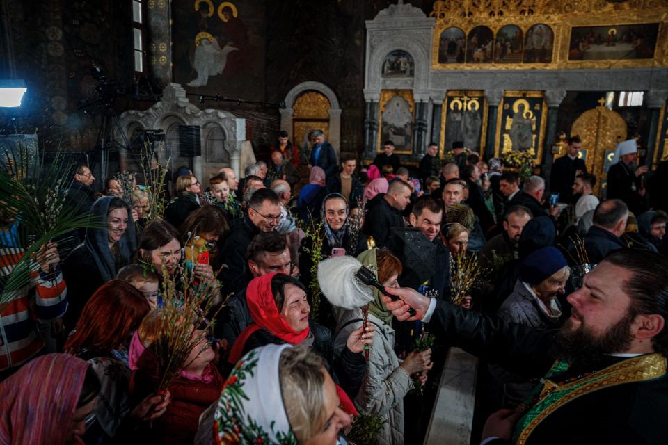 A priest blesses people during an Orthodox Palm Sunday service at the Refectory Church of Saint Anthony and Theodosius in a medieval cave monastery in Kyiv, Ukraine on April 9, 2023.