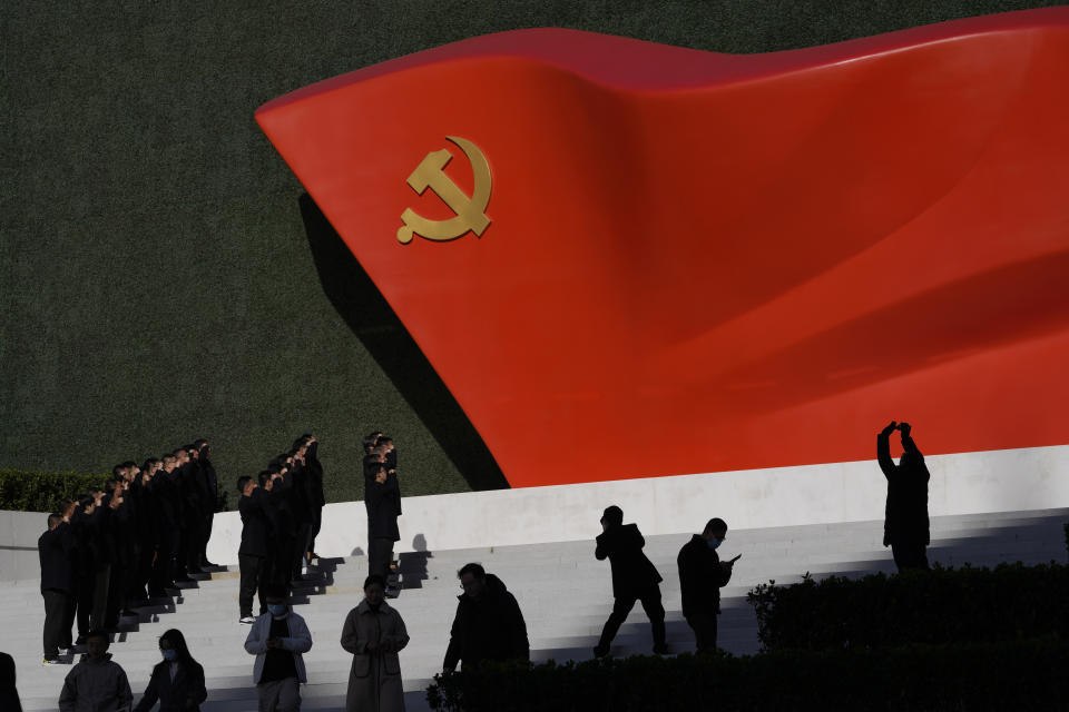 Chinese Communist Party members pose for photos with a sculpture of the party flag outside the Museum of the Communist Party of China of China here in Beijing, China, Friday, Nov. 12, 2021. Chinese leader Xi Jinping emerges from a party conclave this week not only more firmly ensconced in power than ever, but also with a stronger ideological and theoretical grasp on the ruling Communist Party's past, present and future. (AP Photo/Ng Han Guan)