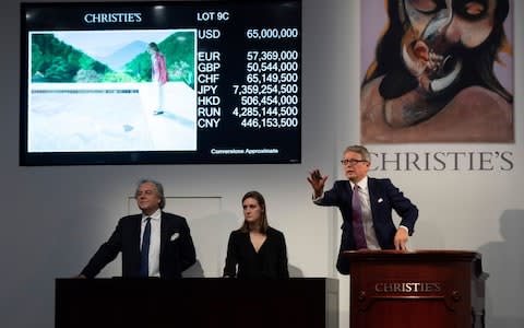 The auctioneer takes bids for the sale of David Hockney's Portrait of an Artist (Pool with Two Figures) during the Post-War and Contemporary Art Evening Sale - Credit: AFP