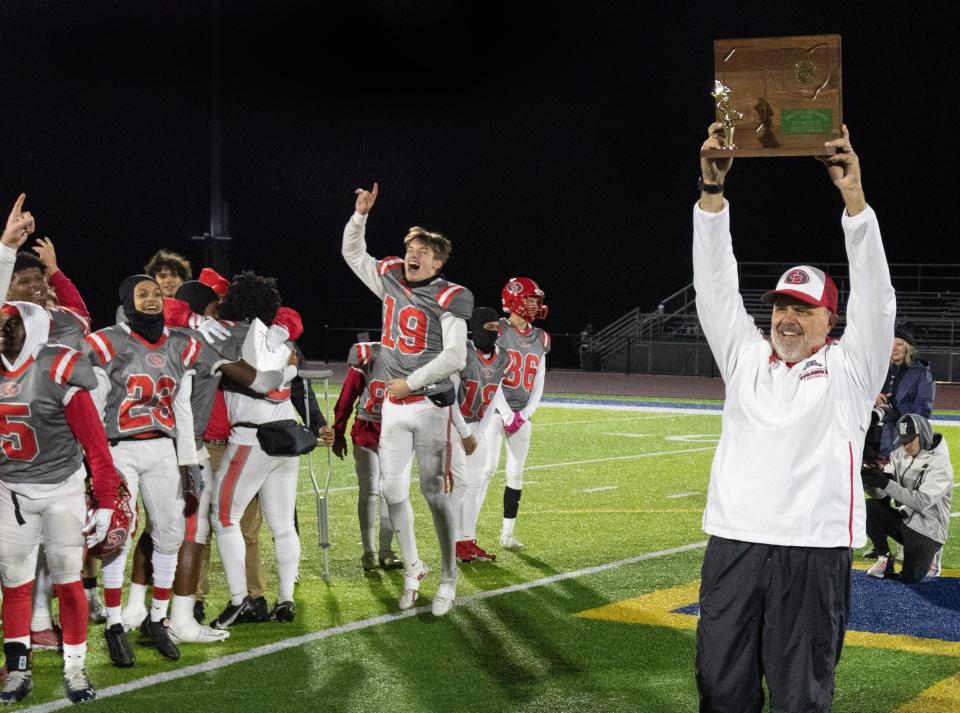 Canton South head coach Matt Dennison holds up the regional championship trophy after defeating Struthers 35-13 on Friday, Nov. 17, 2023.