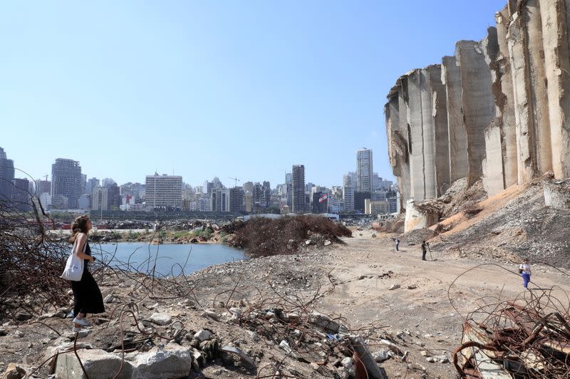 FILE PHOTO: A woman walks on rubble at the site of last year's Beirut port blast, in Beirut