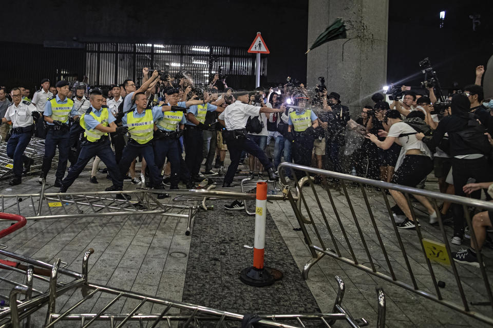 FILE - In this June 10, 2019, file photo, police officers use pepper spray against protesters in a rally against the proposed amendments to the extradition law at the Legislative Council in Hong Kong during the early hours. With Britain the latest country to scrap an extradition treaty with Hong Kong, the focus has returned to concerns over Chinese justice that sparked months of anti-government protests in the semi-autonomous city last year. (AP Photo/Vincent Yu, File)