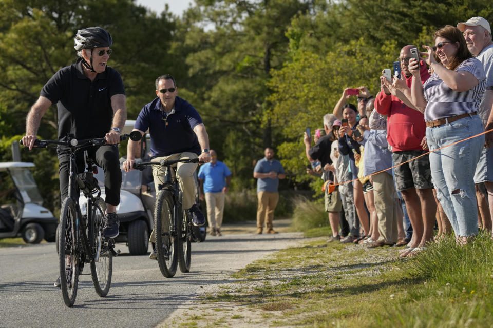 President Joe Biden looks to people gathered along the path as he goes for a bike ride in Gordons Pond State Park in Rehoboth Beach, Del., Sunday, May 14, 2023. (AP Photo/Carolyn Kaster)