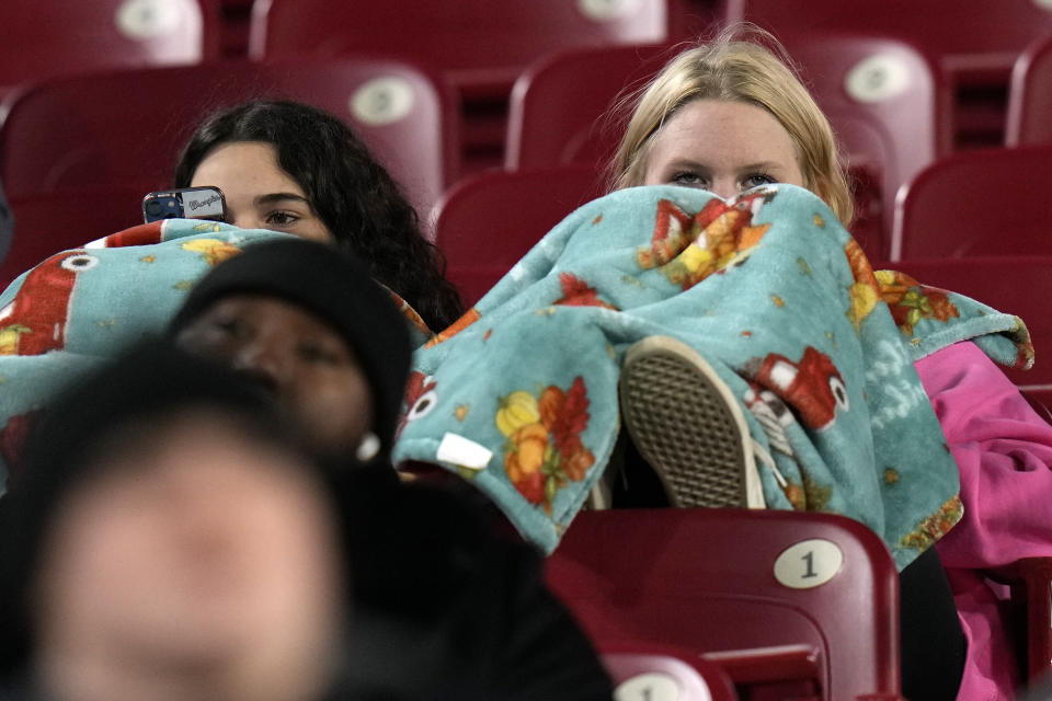 Fans are wrapped up in blankets as they watch in the cold during the first half of the Gasparilla Bowl NCAA college football game between Wake Forest and Missouri Friday, Dec. 23, 2022, in Tampa, Fla. (AP Photo/Chris O'Meara)