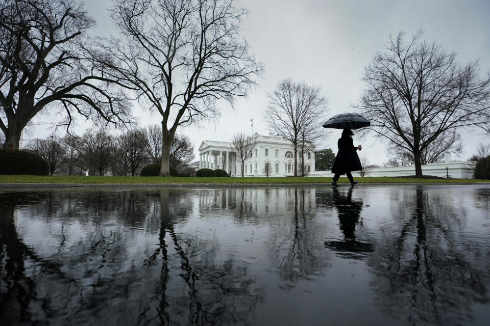 A reporter walks up the driveway toward the White House on a rain-soaked morning in Washington, D.C., Tuesday. (Kevin Lamarque/Reuters)
