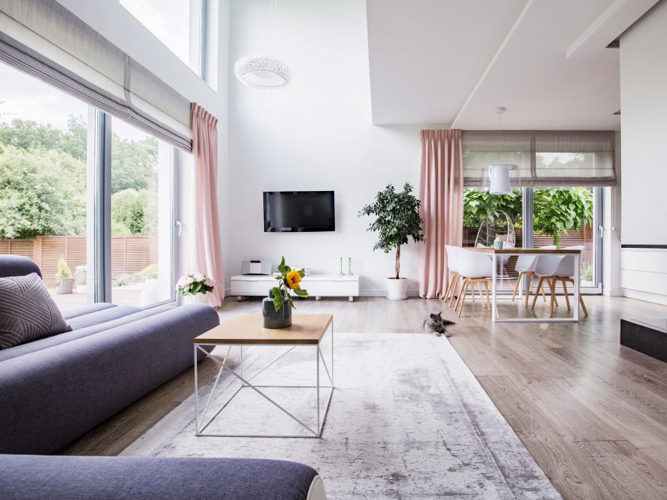 Real photo of a dining area, television and gray couch in open space living room interior