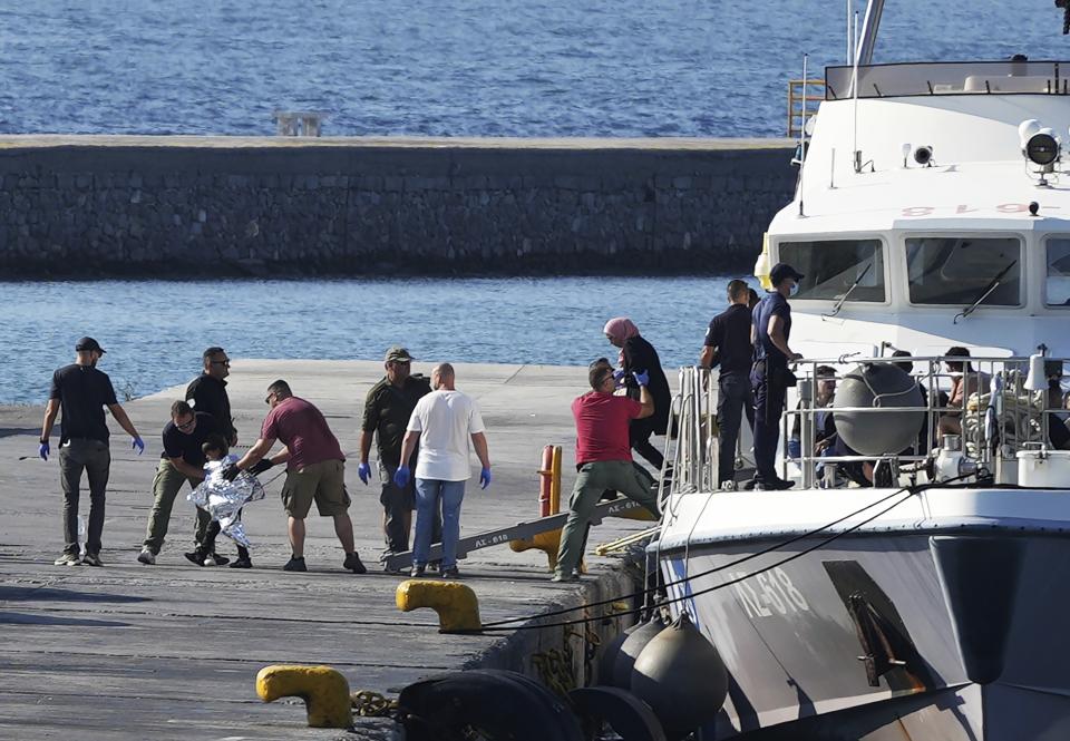 A child escorted by coast guard officers disembarks with other migrants from a vessel after a rescue operation, at the port of Mytilene, on the northeastern Aegean Sea island of Lesbos, Greece, Monday, Aug. 28, 2023. Greek authorities say four people died and 18 were rescued Monday after a boat carrying migrants apparently sank northeast of the Greek island of Lesbos, which lies near the Turkish coast. (AP Photo/Panagiotis Balaskas)