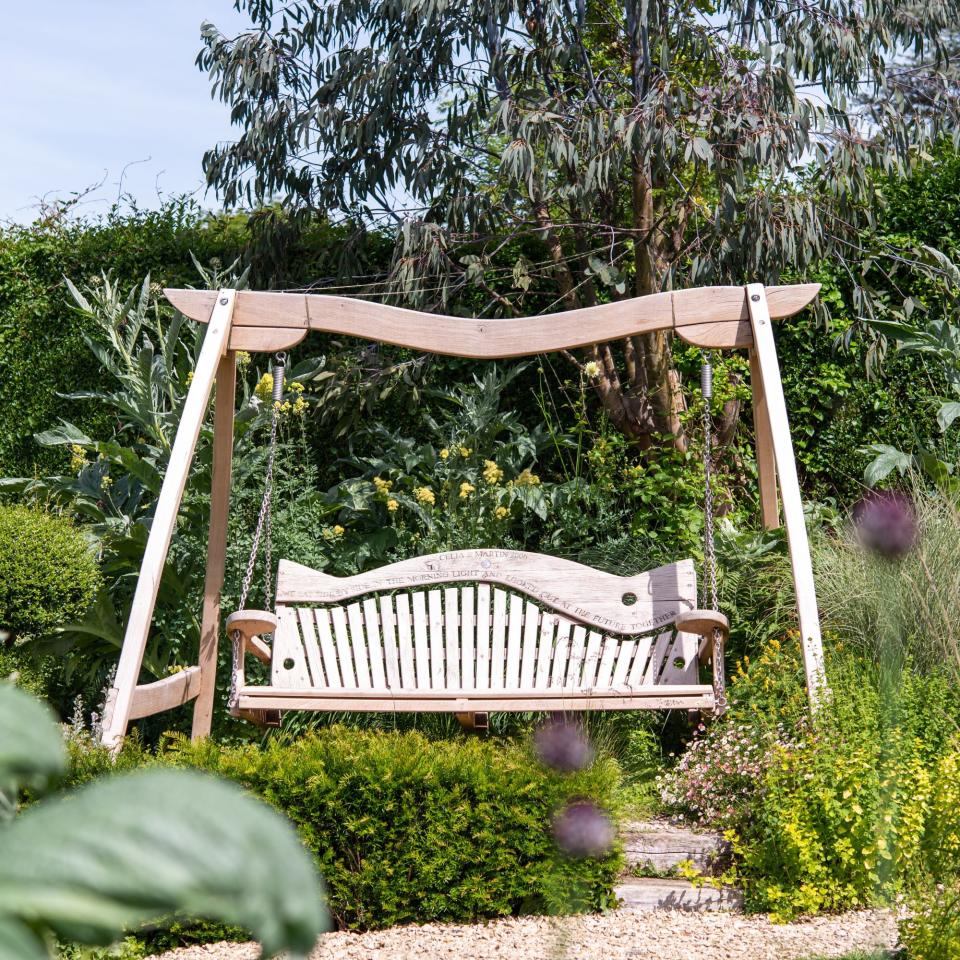 Wooden garden bench surrounded by bushes and trees