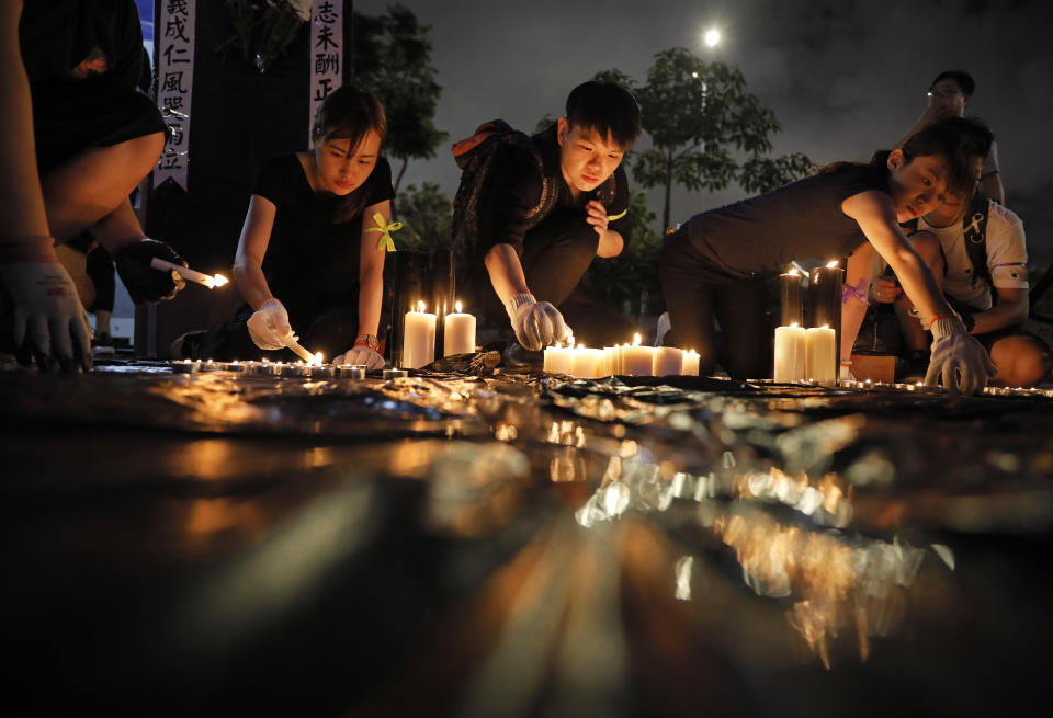 People light candles during a vigil to mourn the recent suicide of a woman due to the government's policy on the extradition bill, in Hong Kong Saturday, July 6, 2019. A vigil is being held in Hong Kong for a woman who fell to her death this week, one of three apparent suicides linked to ongoing protests over fears that freedoms are being eroded in this semi-autonomous Chinese territory. (AP Photo/Vincent Yu)