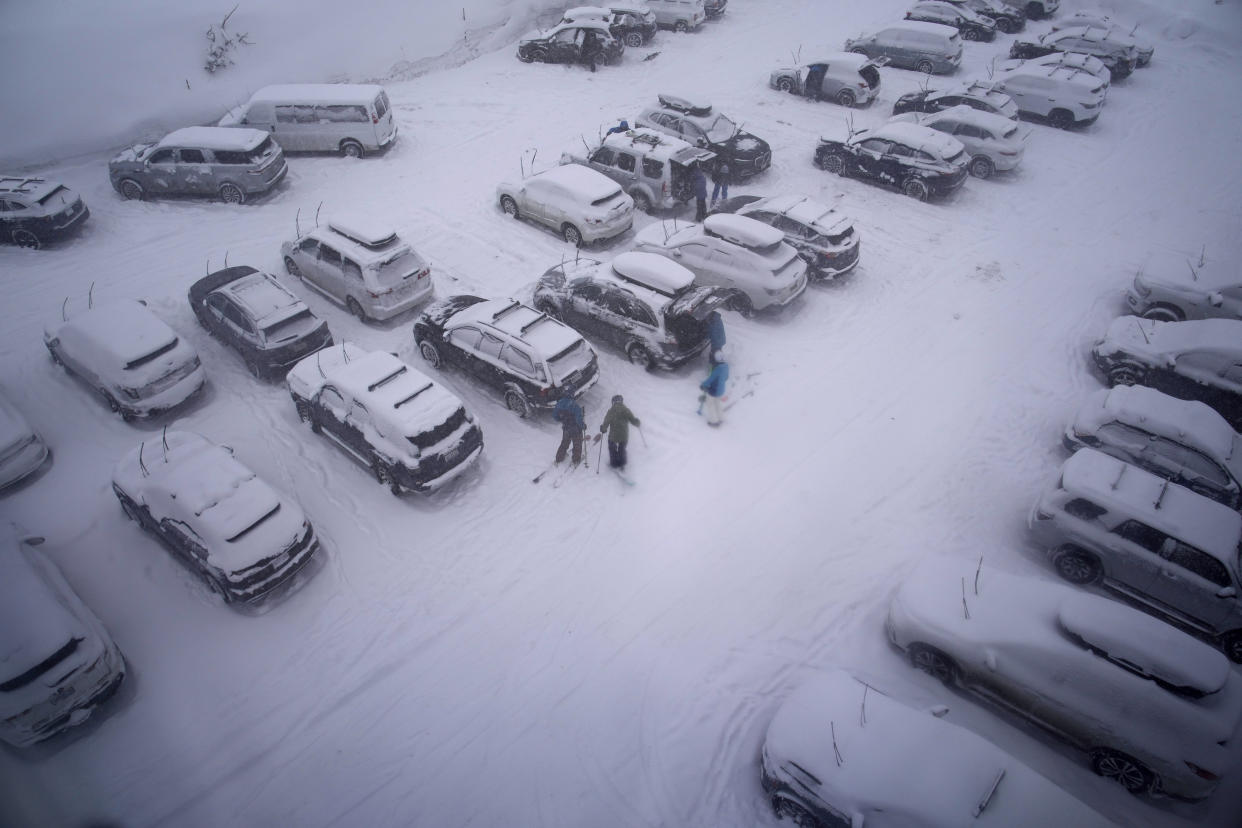 People stand in the parking area of the Alpine Base Area at Palisades Tahoe during a winter storm Friday, Feb. 24, 2023, in Alpine Meadows, Calif. California and other parts of the West are facing heavy snow and rain from the latest winter storm to pound the United States. (AP Photo/John Locher)