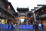 People walk past a checkpoint for temperature checks and mandatory face masks at the Qinhuai scenic zone in Nanjing in eastern China's Jiangsu province, Saturday, Jan. 25, 2020. The virus-hit Chinese city of Wuhan, already on lockdown, banned most vehicle use downtown and Hong Kong said it would close schools for two weeks as authorities scrambled Saturday to stop the spread of an illness that is known to have infected more than 1,200 people and killed 41, according to officials. (Chinatopix via AP)