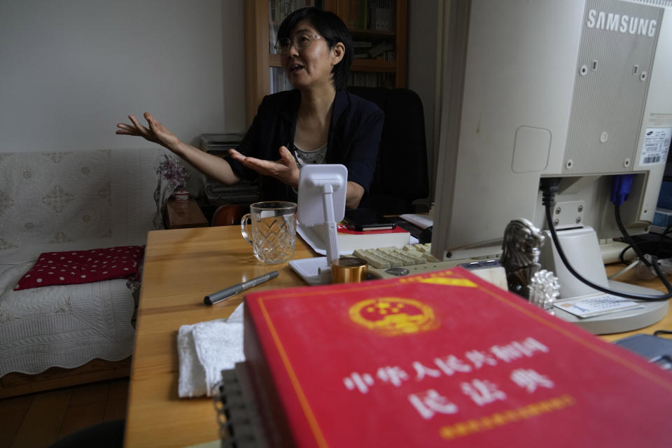 Activist Wang Yu explains her difficulties traveling in China because of the country's health code apps, speaking during an interview, Thursday, June 30, 2022, in Beijing. A copy of the Chinese legal dictionary lies in the foreground. (AP Photo/Ng Han Guan)