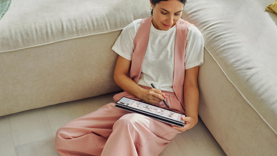 A person sits on a couch and exercises using the HP OmniBook Ultra Flip 14-inch.