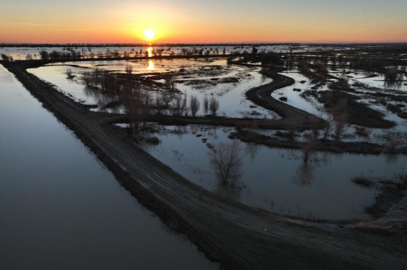 DUNNIGAN, YOLO COUNTY, CALIFORNIA-Jan. 21, 2023-In Yolo County, near the town of Dunnigan, officials from the state Department of Water Resources are working with farmers on a project to recharge the underground aquifers. The water is allowed to percolate into the ground to replenish the aquifers, while also providing habitat for threatened shore birds and other birds. Sunrise over the flooded fields that are part of the program on Jan. 21, 2023. (Carolyn Cole / Los Angeles Times)