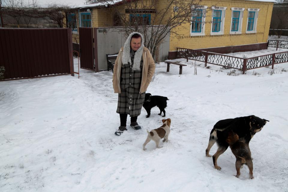 A woman walks with her dogs on the territory controlled by pro-Russian militants near frontline with Ukrainian government forces in Slavyanoserbsk, Luhansk region, eastern Ukraine, on Jan. 25, 2022. Ukraine's leaders sought to reassure the nation that a feared invasion from neighboring Russia was not imminent, even as they acknowledged the threat is real and prepared to accept a shipment of American military equipment Tuesday to shore up their defenses.