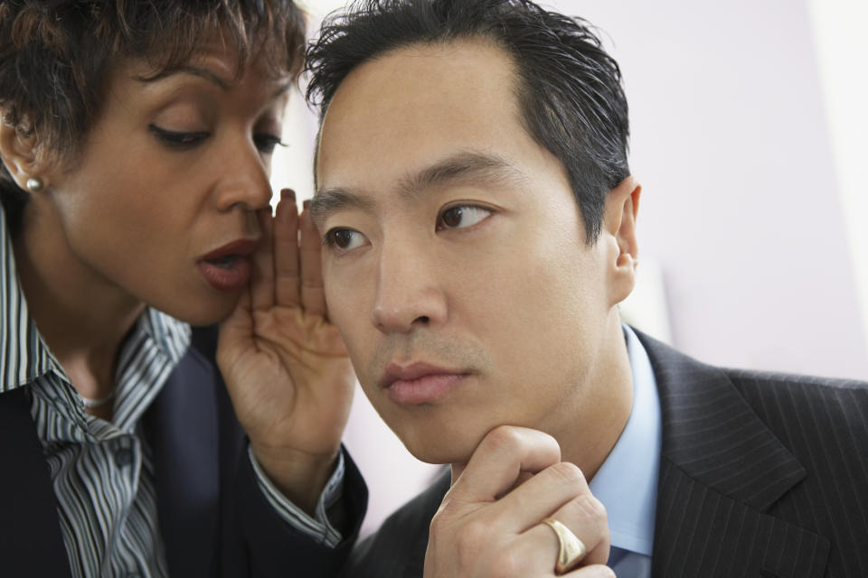 businesswoman whispering in a businessman's ear