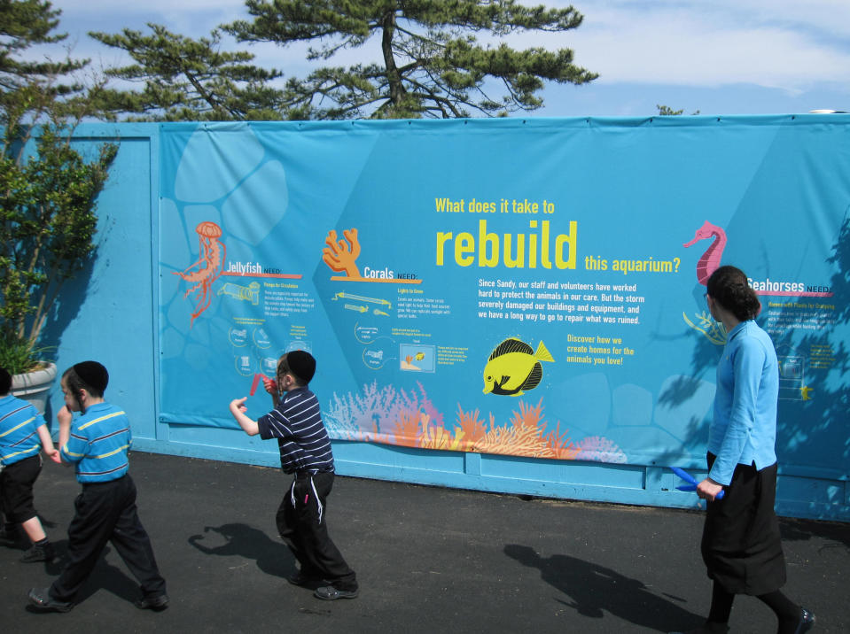 In this May 31, 2013 photo, a sign outside of Coney Island's New York Aquarium details rebuilding efforts at the aquarium in the Brooklyn borough of New York. Eight months after Superstorm Sandy hit New York City, Coney Island’s rides, eateries and beach are getting plenty of visitors, and there are even a few new attractions like a carousel and a store for fans of the Nets basektball team. (AP Photo/Beth Harpaz)