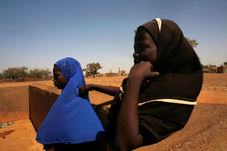 Girls stand near a water pump in the village of Nedgo, near Ouagadougou, Burkina Faso February 16, 2018. REUTERS/Luc Gnago