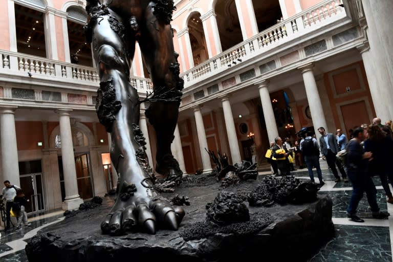 People look at "Demon with Bowl" by British artist Damien Hirst during the press presentation of his exhibit "Treasures from the Wreck of the Unbelievable" at the Pinault Collection in Punta della Dogana and Palazzo Grassi in Venice on April 6, 2017