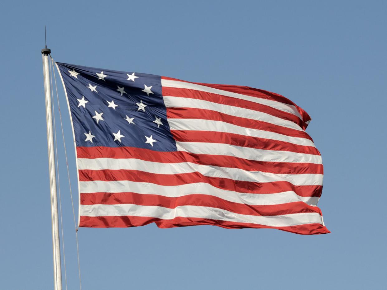 "A 15 star/15 stripe US flag flying at Ft. McHenry in Baltimore, MD against a blue sky"