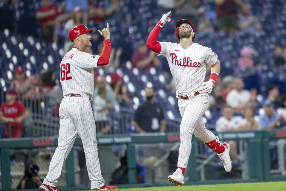 Philadelphia Phillies' Bryce Harper, right, gestures to the sky with third base coach Dusty Wathan, left, after hitting a home run during the fourth inning of a baseball game against the Atlanta Braves, Tuesday, June 8, 2021, in Philadelphia. (AP Photo/Laurence Kesterson)