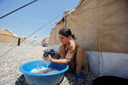 A displaced Iraqi girl from Talafar washes her clothes in Salamya camp, east of Mosul, Iraq August 6, 2017. REUTERS/Khalid Al-Mousily