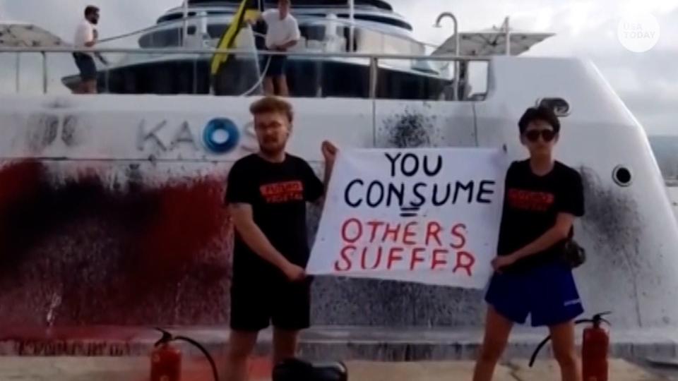 Activists by Spanish environmental group Futuro Vegetal spray paint a superyacht in Ibiza and hold a sign that says "You consume others suffer."